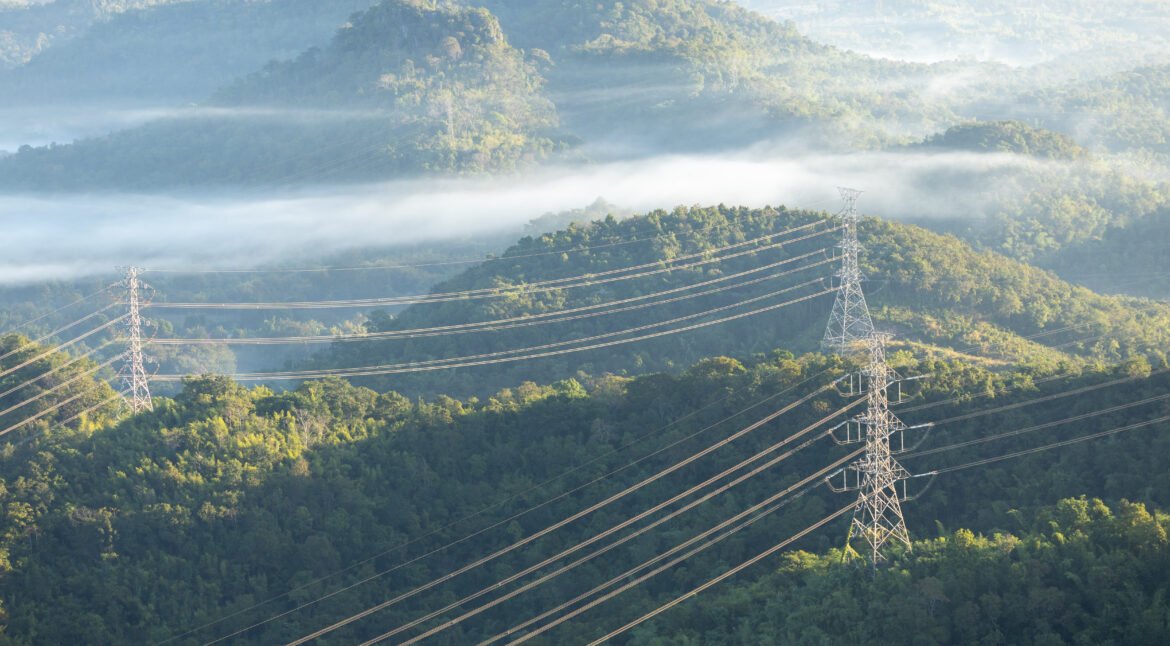 High voltage electric power tower in a green agricultural landscape at sunset
