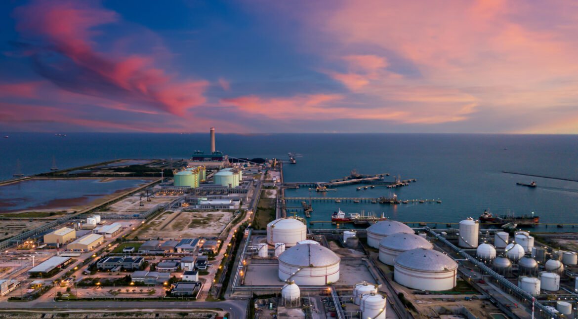 Aerial view oil terminal and coal power plant station in sea, White oil storage tank chemical petroleum petrochemical refinery product, Tanker ship at deep ocean seaport terminal.